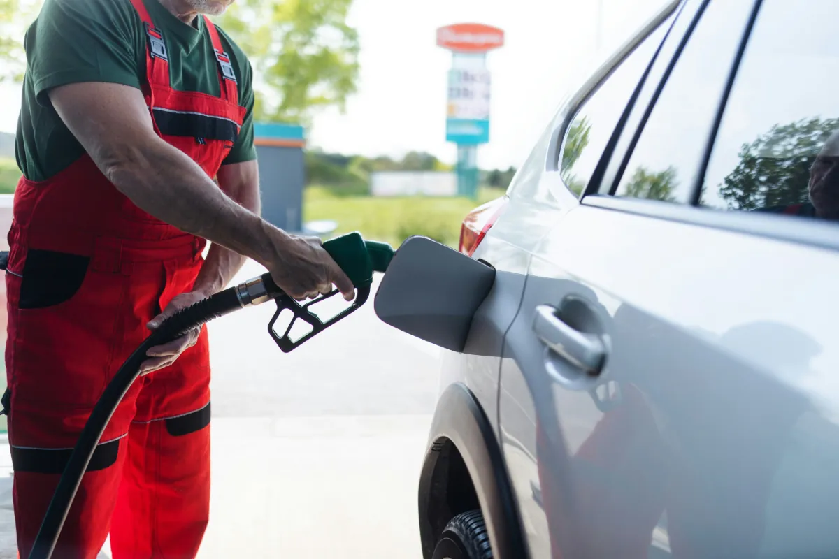 Professional fuel system service - technician refueling vehicle at gas station